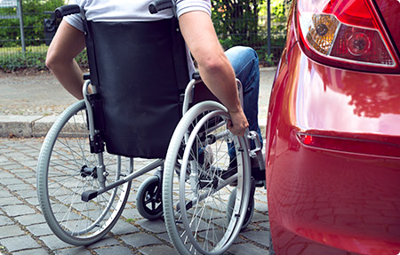 Rollstuhlfahrer neben einem Auto – barrierefrei mobil
